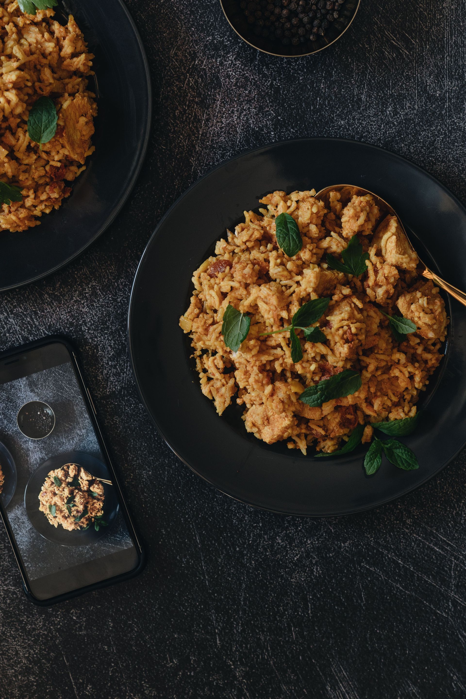 A flavorful chicken biryani dish served with mint garnish on a dark plate.