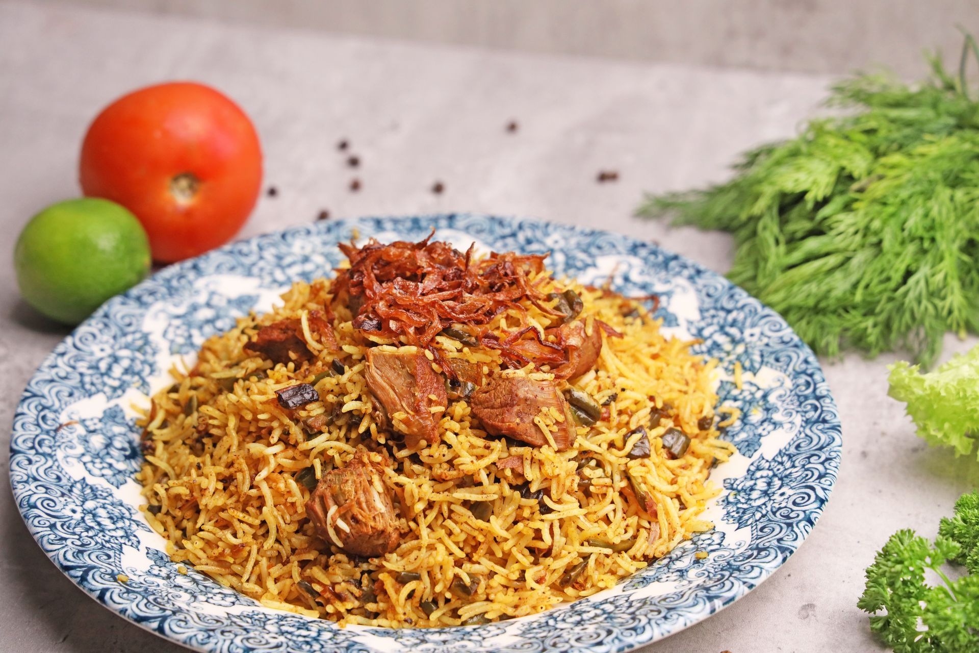 A close-up of flavorful lamb biryani served on a ceramic plate with herbs and vegetables.